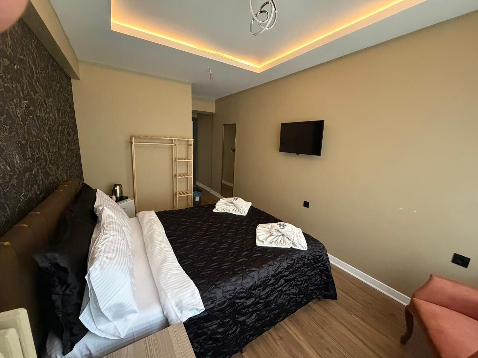 A hotel room with a bed, a wardrobe, a television, and a seating area.