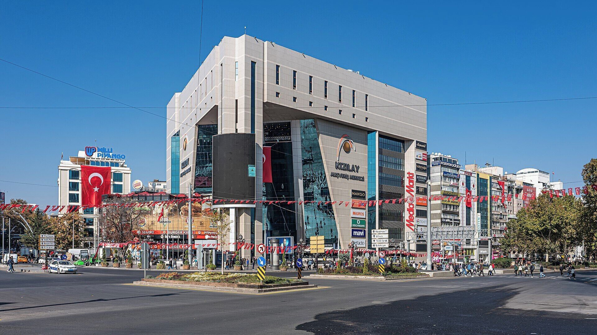 A modern building with multiple commercial signs, including a prominent 'Mango' sign.