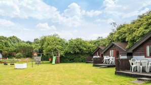 A campsite with wooden cabins, a swing set, and a picnic table area. - 4 Person Holiday Park Home in Grindsted (Grindsted)