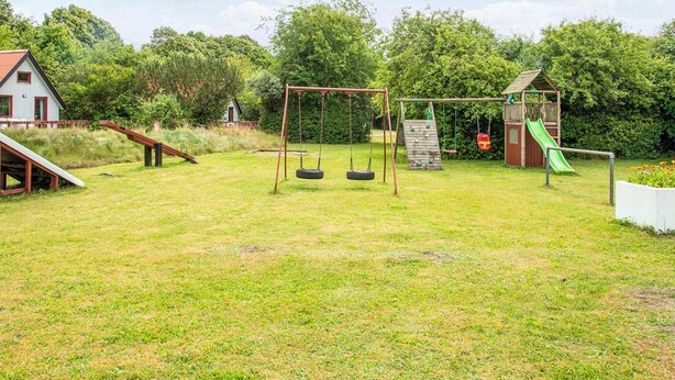 A playground with swings, a slide, and a small playhouse. - 6 Person Holiday Park Home in Grindsted (Grindsted)