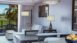 A modern living room with a sofa, a coffee table, and a dining area with a bowl of fruit.