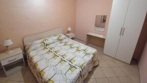 Una camera da letto con un letto, un comodino, una scrivania e un armadio.