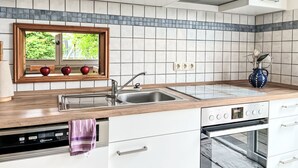 A modern kitchen with a window, a sink, a stove, and a dishwasher.