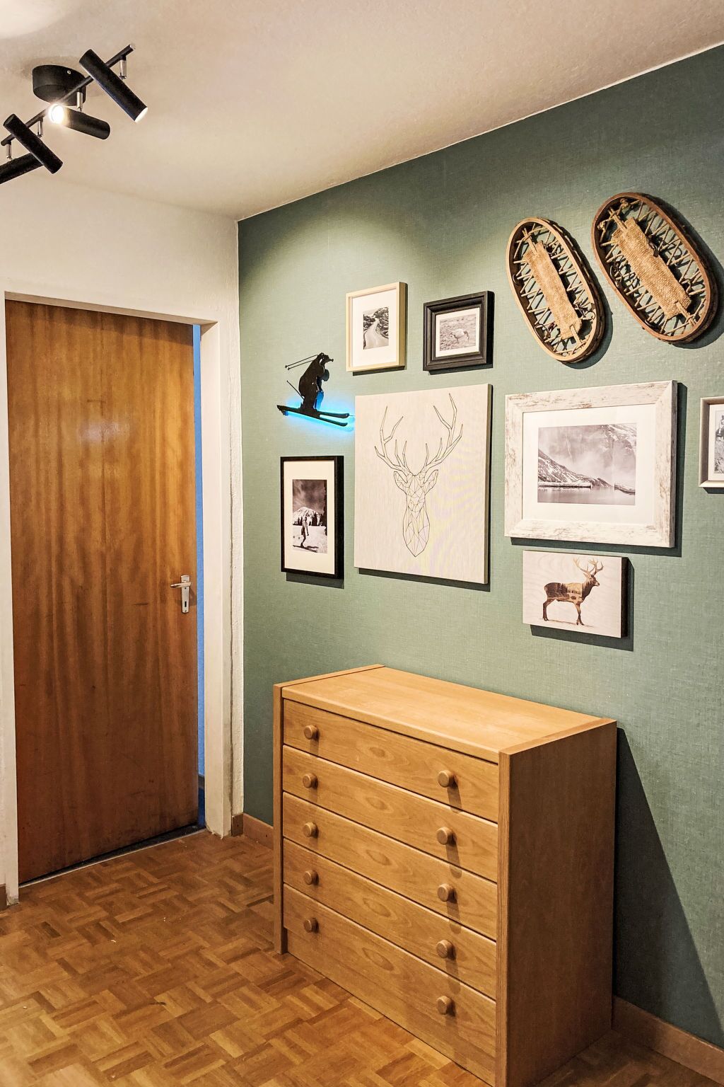 Un pasillo con un aparador de madera, cuadros en la pared y un reloj.