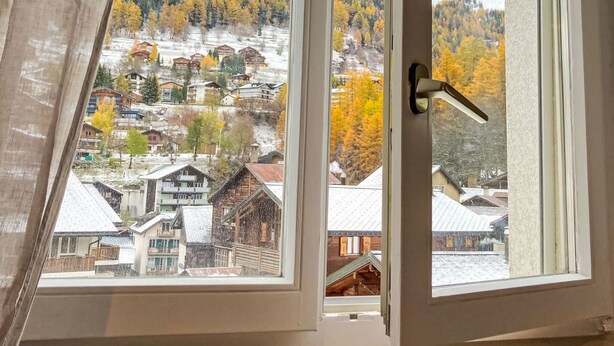 A window with a view of a snowy mountain landscape and autumn-colored trees. - Apartment Dala by Interhome (Leukerbad)