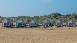 A row of beach cabanas with a clear view of the beach and dunes in the background.