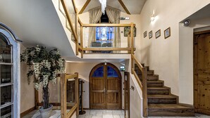 A spacious foyer with a wooden staircase leading to a loft.
