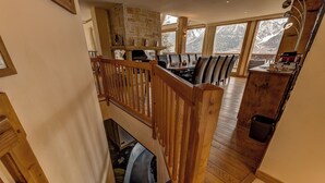 A spacious dining area with a high wooden ceiling and a stone fireplace.