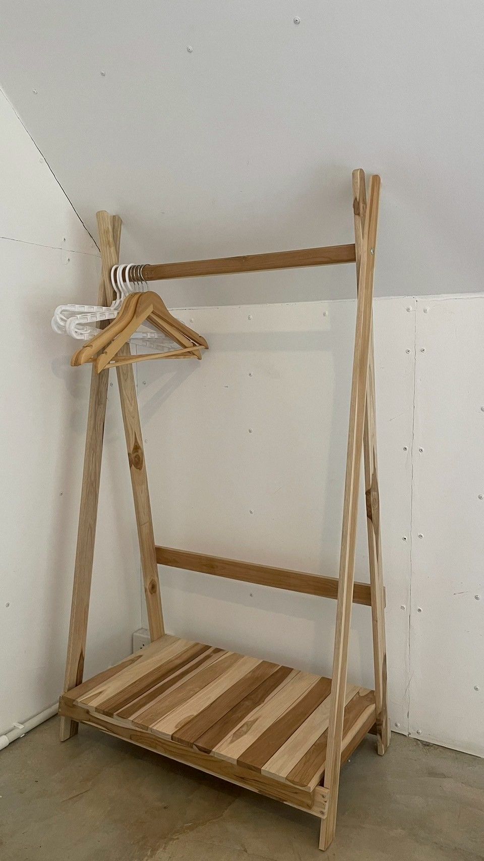 Een houten, losstaand, open wandrek met een witte beugel.