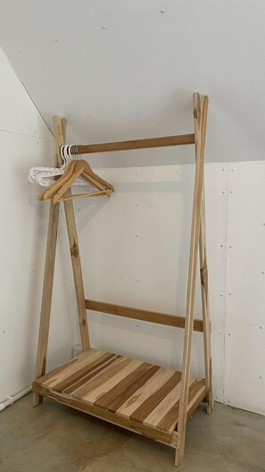 Una estantería de madera independiente, de estructura abierta, con un perchero blanco.