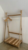 Una estantería de madera independiente, de estructura abierta, con un perchero blanco.