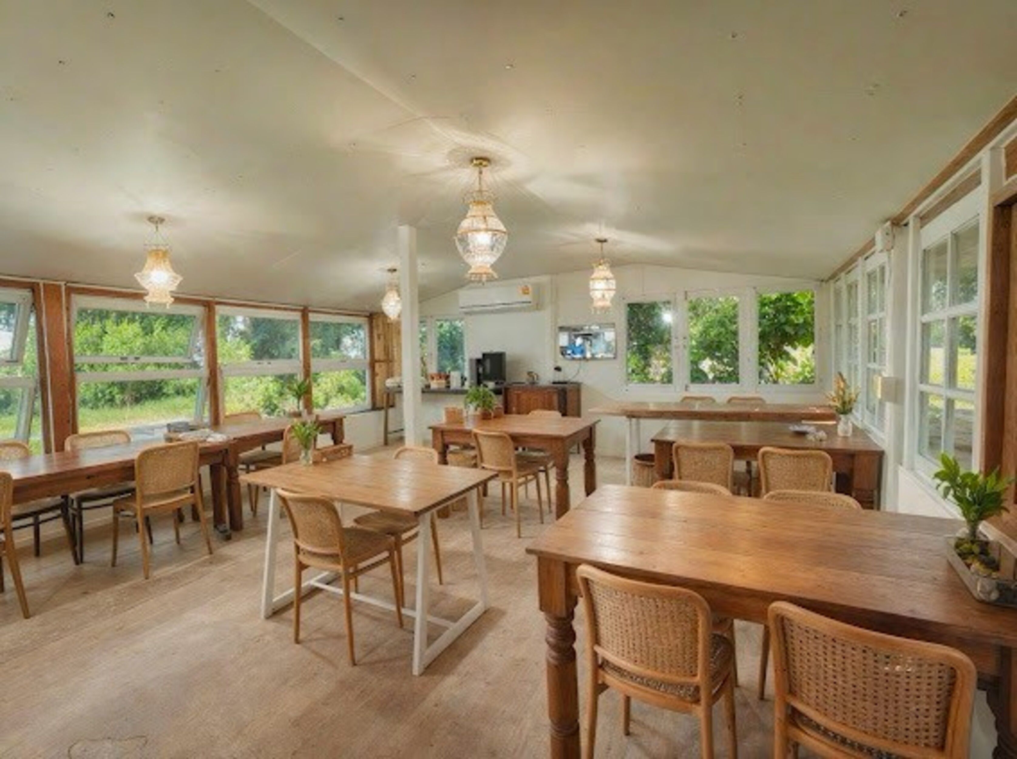 Un comedor amplio con mesas y sillas de madera, ventanas grandes y lámparas colgantes.