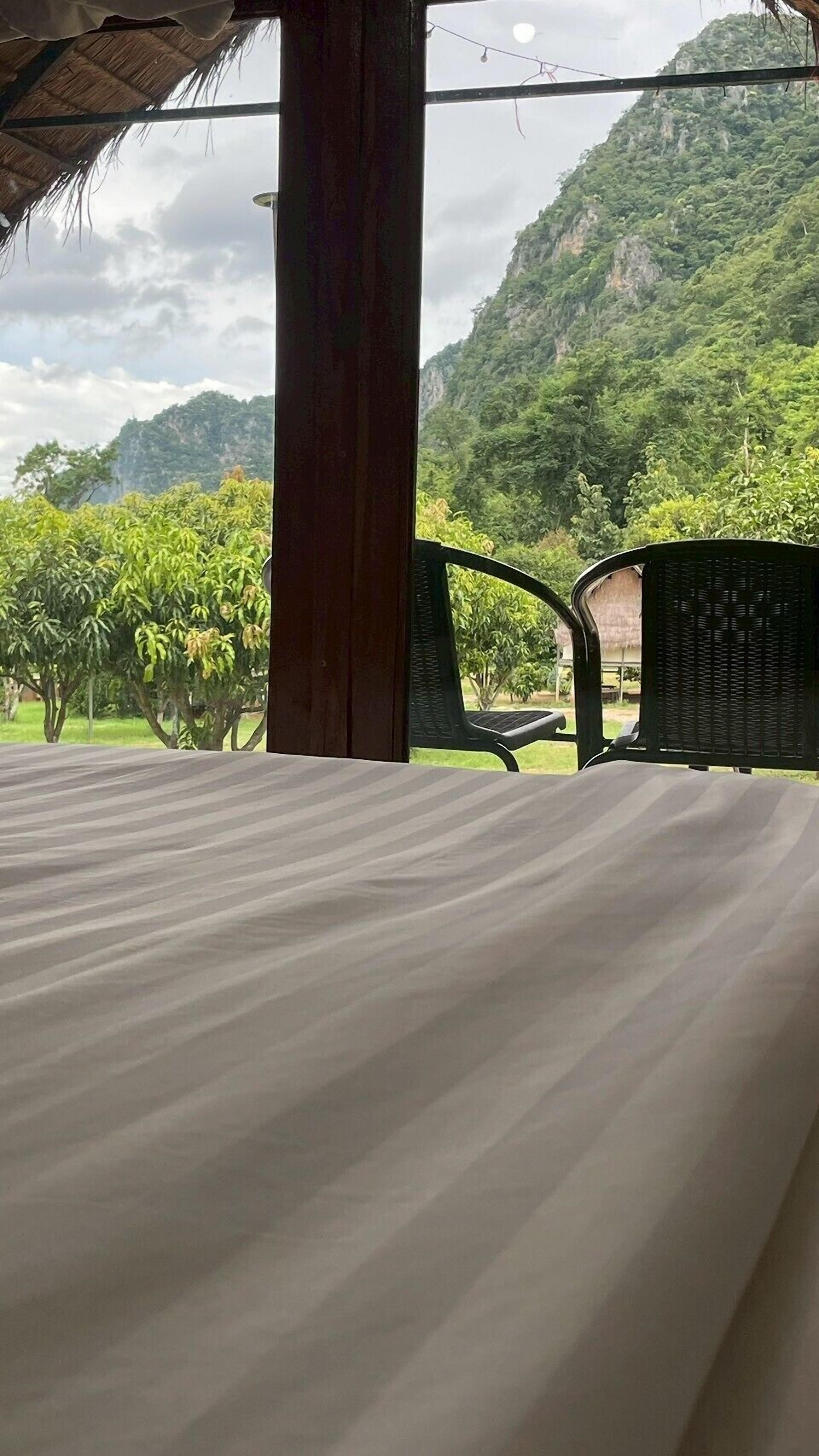 A room with a bed, a chair, and a view of a lush green landscape with mountains.