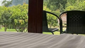 A room with a bed, a chair, and a view of a lush green landscape with mountains.