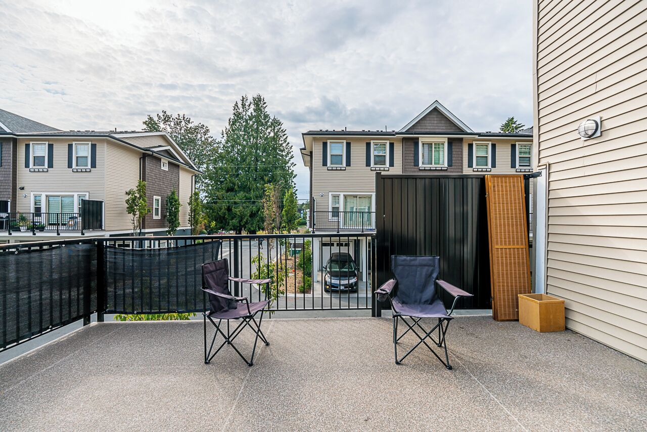 A covered patio with two folding chairs, a wooden bench, and a small table.