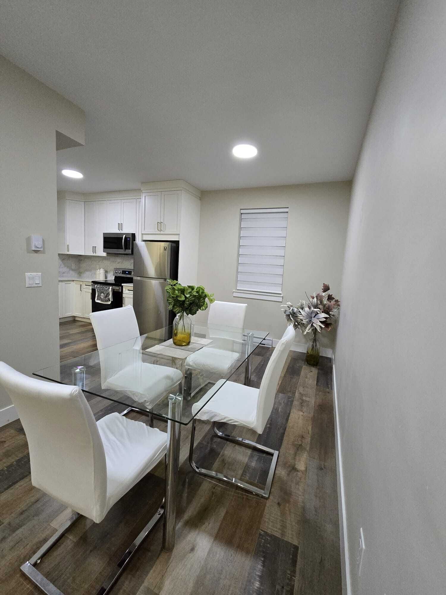 A modern kitchen with white cabinets, a microwave, and a refrigerator.