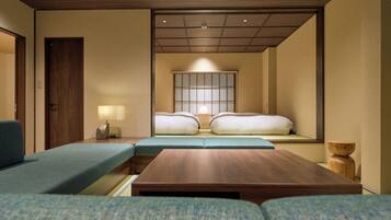 Ein modernes Hotelzimmer mit einer Couch, einem Holztisch, einem Nachttisch mit Lampe und einem traditionellen japanischen Shoji-Bildschirm hinter dem Bett.