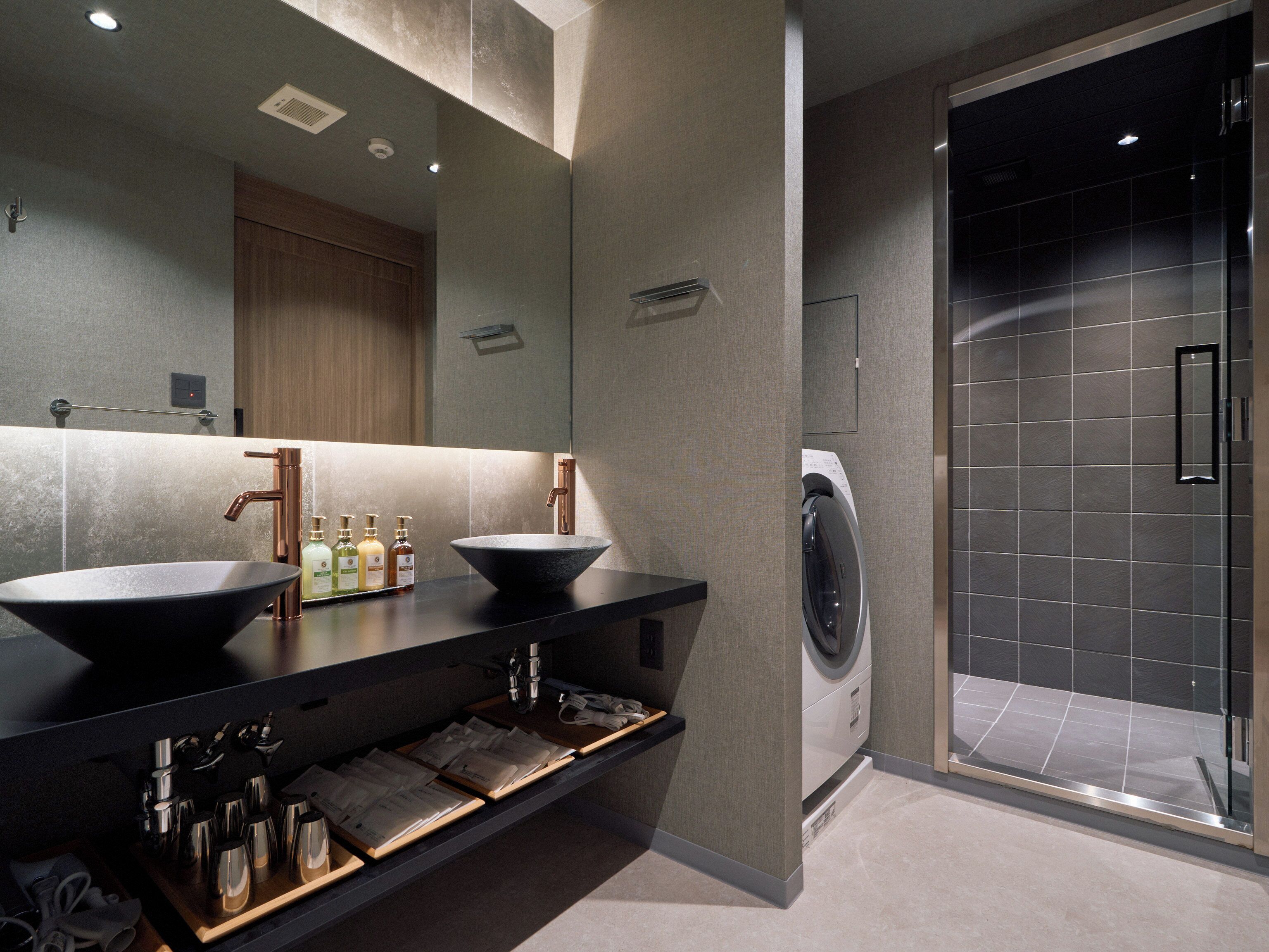 A modern bathroom with two sinks, a large mirror, and a built-in washing machine.