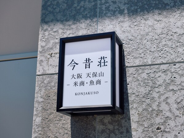 A framed sign with text on a stone wall. - KONJAKUSO Osaka Tempozan KOMESHOU UOSHOU (Osaka)