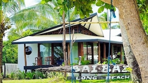 A bungalow with a large porch, surrounded by lush greenery and palm trees. - BAIBAI (San Vicente)