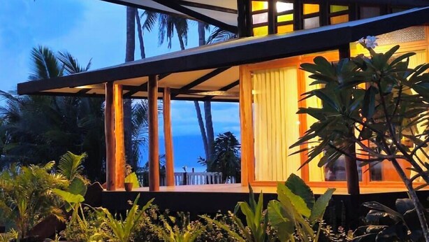 A modern house with a covered porch, surrounded by tropical vegetation and palm trees. - BAIBAI (San Vicente)