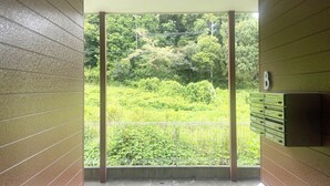 A corridor with a view of a lush green forest through a glass door.