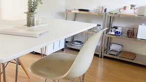 A modern kitchen with a white table, a beige chair, and a potted plant.