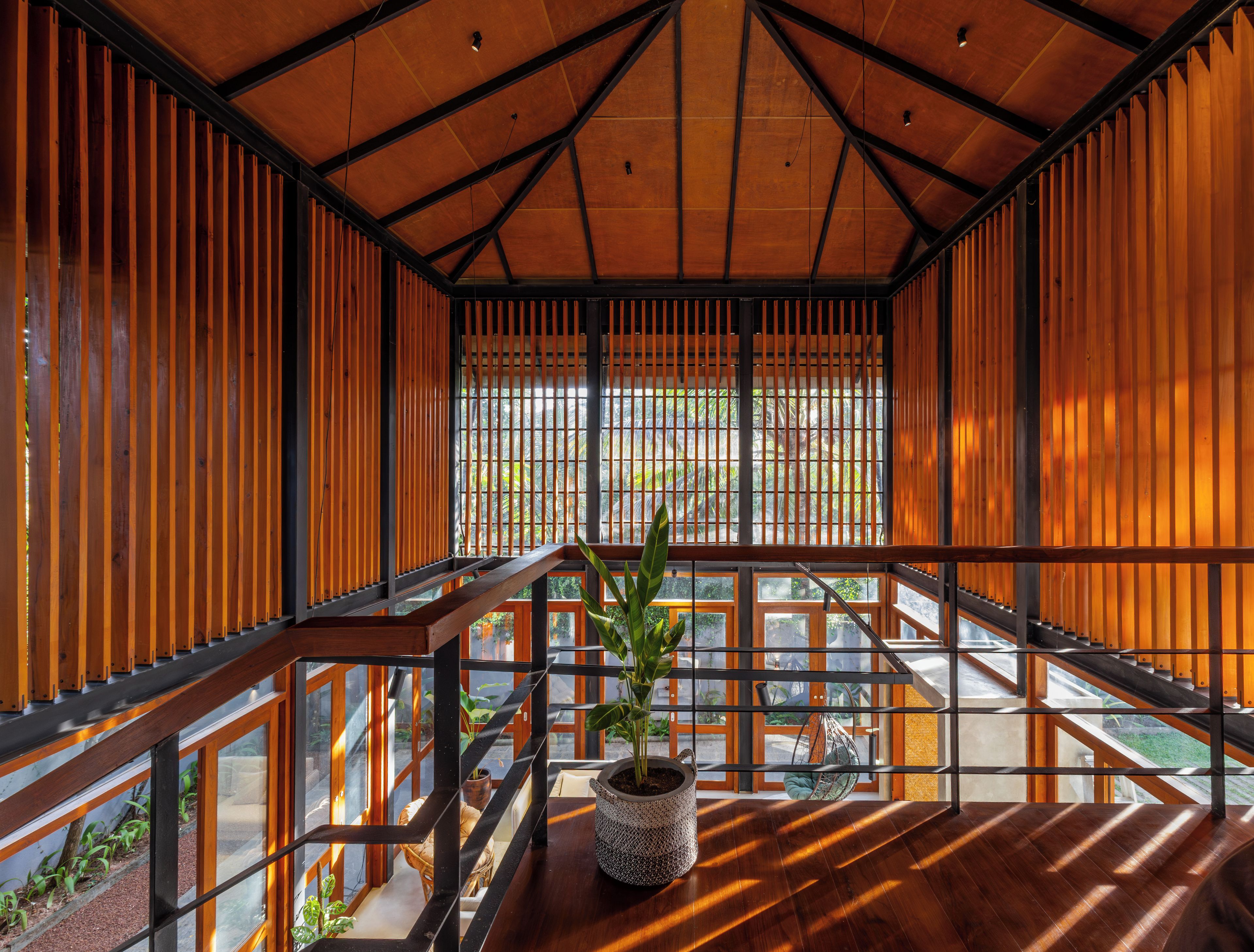 A modern interior with a wooden ceiling, a staircase, and a potted plant.