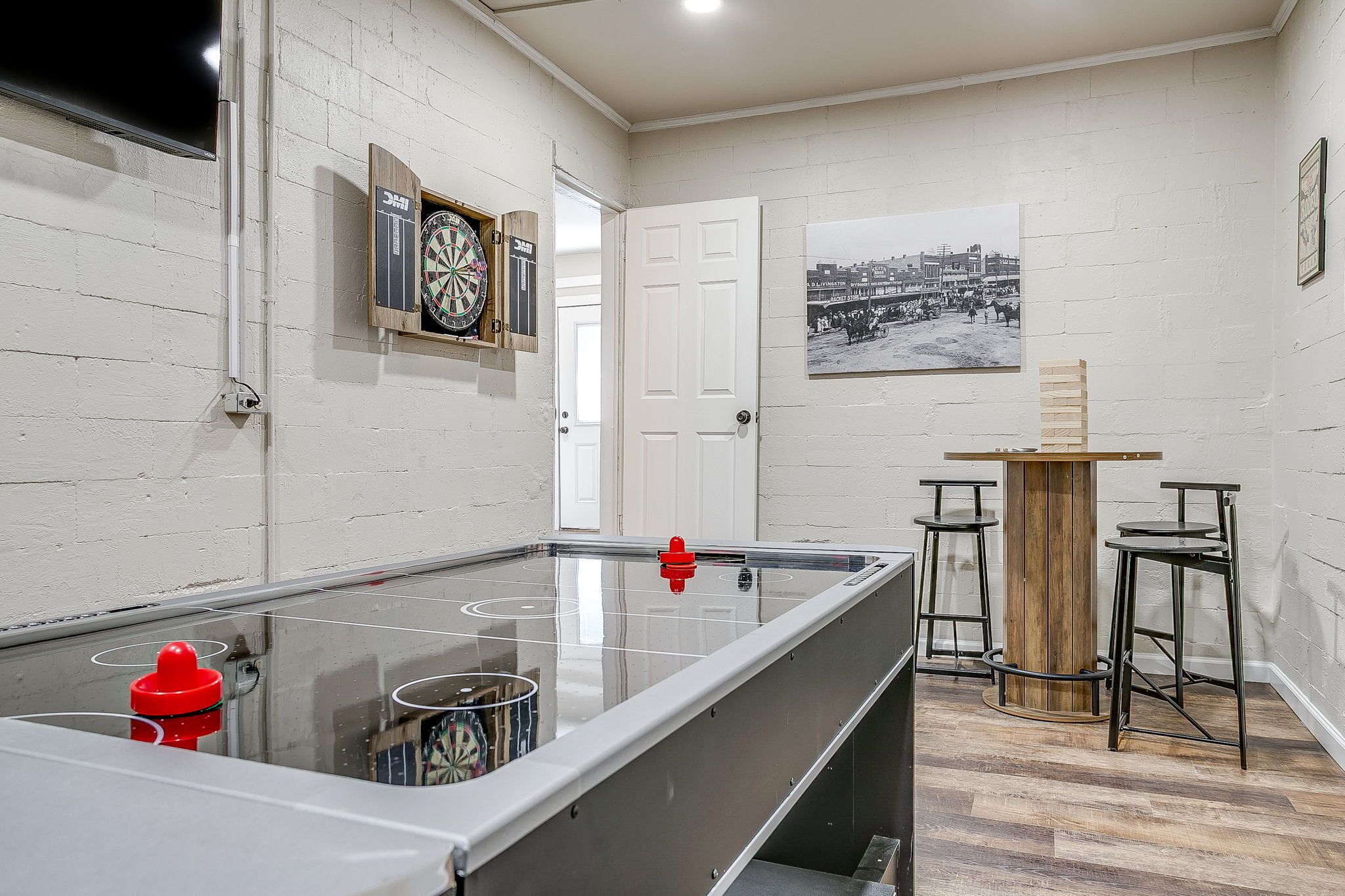 A pool table with a dartboard and a framed photo on the wall.