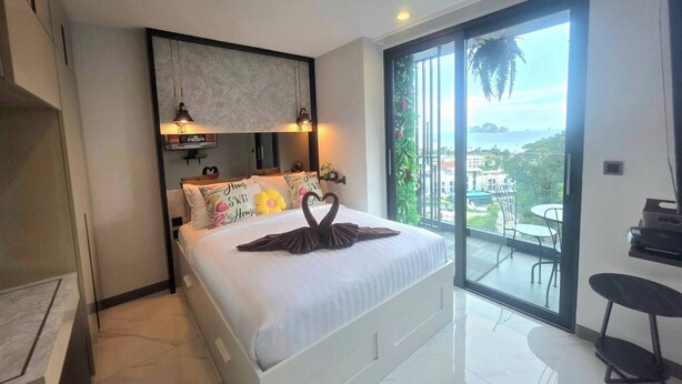 Un dormitorio moderno con una cama grande, un balcón con vistas y una zona de comedor con mesa y sillas.