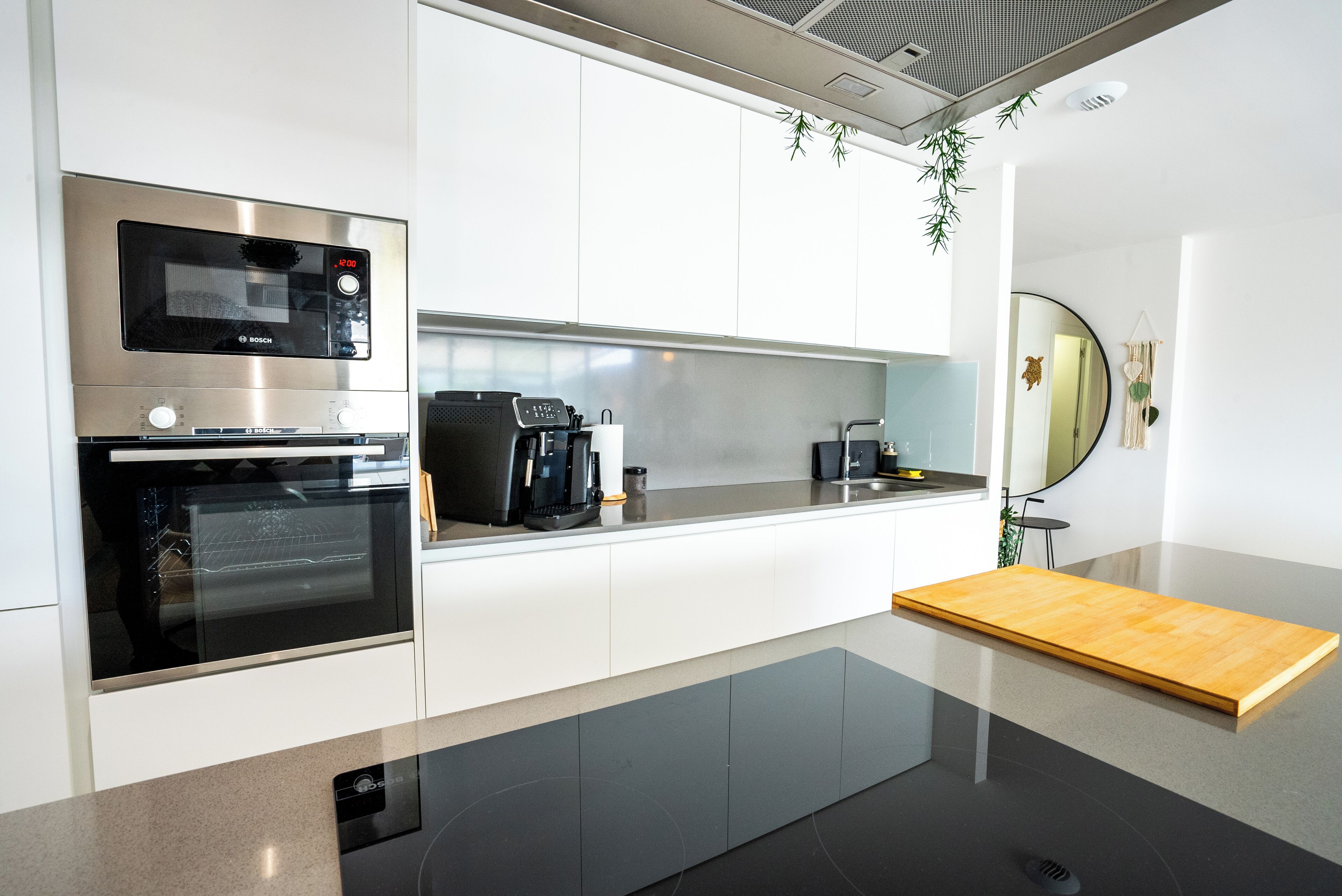 Una cocina moderna con electrodomésticos integrados, encimera de madera y un pequeño comedor.
