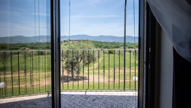 Ein Balkon mit Blick auf eine grüne Landschaft und ferne Berge.