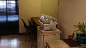 A kitchen with a sink, a countertop, a basket of dishes, a plant, and a wall clock. - Cozy City Stay in Baguio (Baguio)