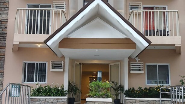 A multi-story building with a central entrance, stone steps, and potted plants. - Cozy City Stay in Baguio (Baguio)