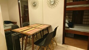 A compact room with a wooden table, two chairs, a heater, and a bunk bed with a curtain. - Cozy City Stay in Baguio (Baguio)