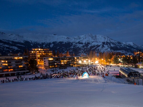 A snow-covered mountain with a ski resort and buildings in the background.