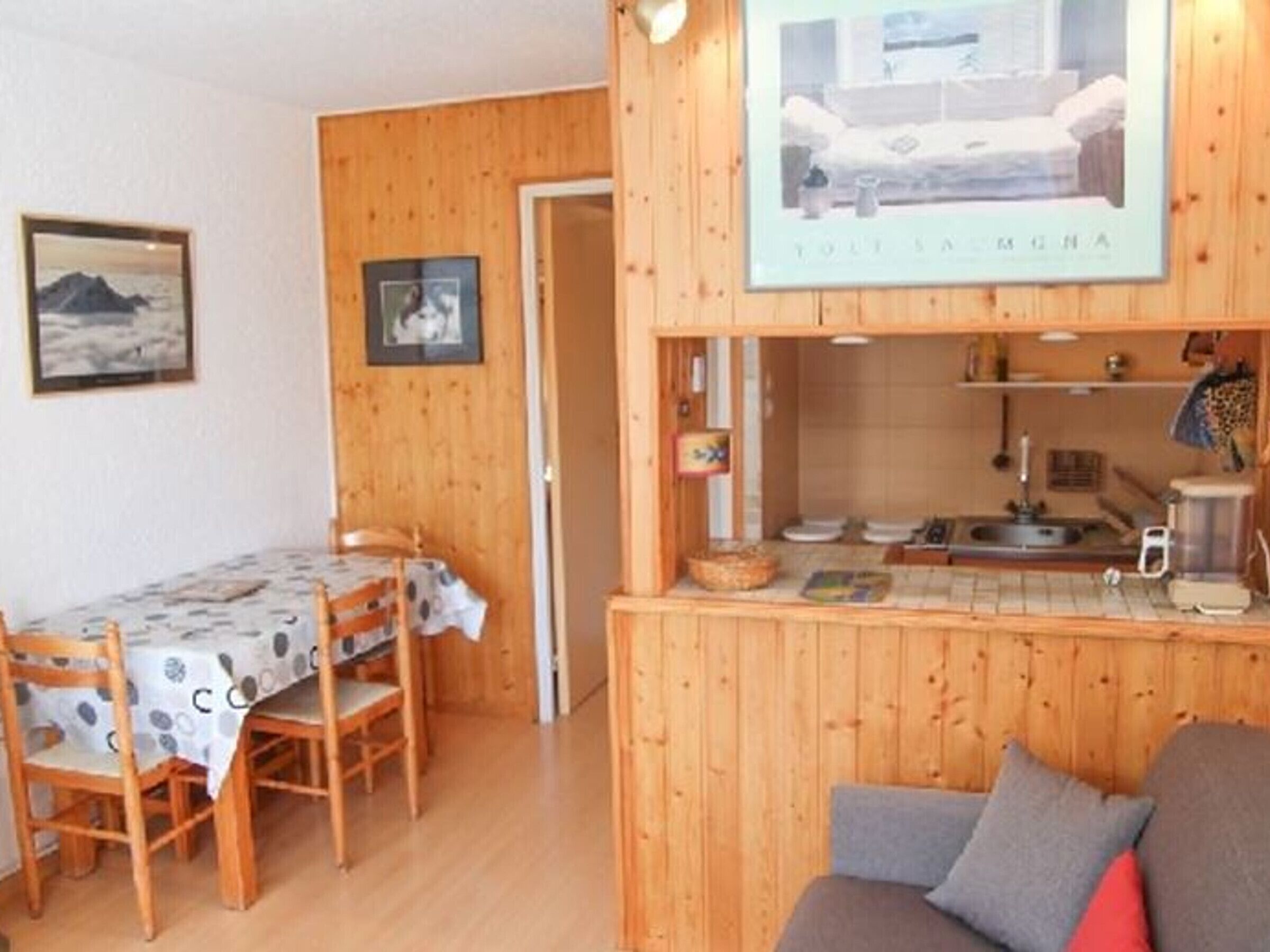 A cozy room with a wooden interior, a dining area with a table and chairs, and a kitchenette with a sink and stove.