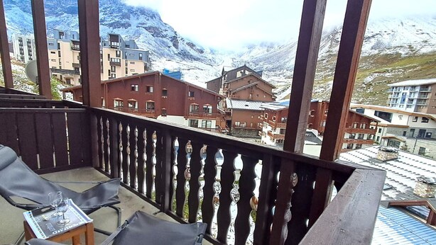 A balcony with a view of snow-covered mountains and buildings.