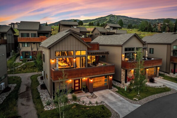 A modern residential building with a two-story layout, large windows, and a visible garage.