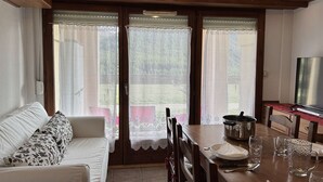 A cozy living area with a sofa, dining table, and a TV.