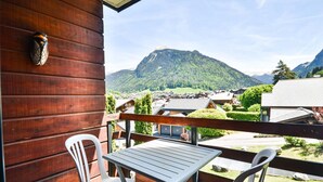 A wooden balcony with a table and two chairs, overlooking a mountainous landscape and a village. - Central Morzine apartment, 6 pers, south balcony (Morzine)