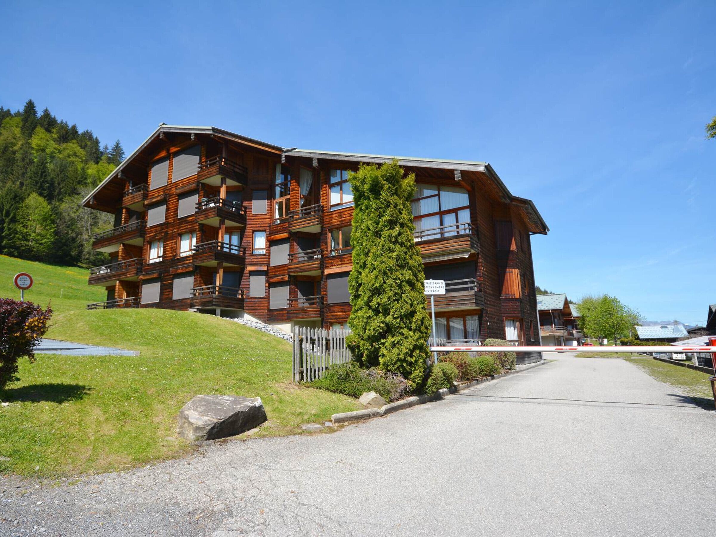Un immeuble en bois à plusieurs étages, doté de balcons, une allée gravillonnée et un ciel dégagé.