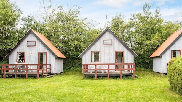 Three wooden cabins with red-framed windows and doors, each with a small porch and a metal roof.