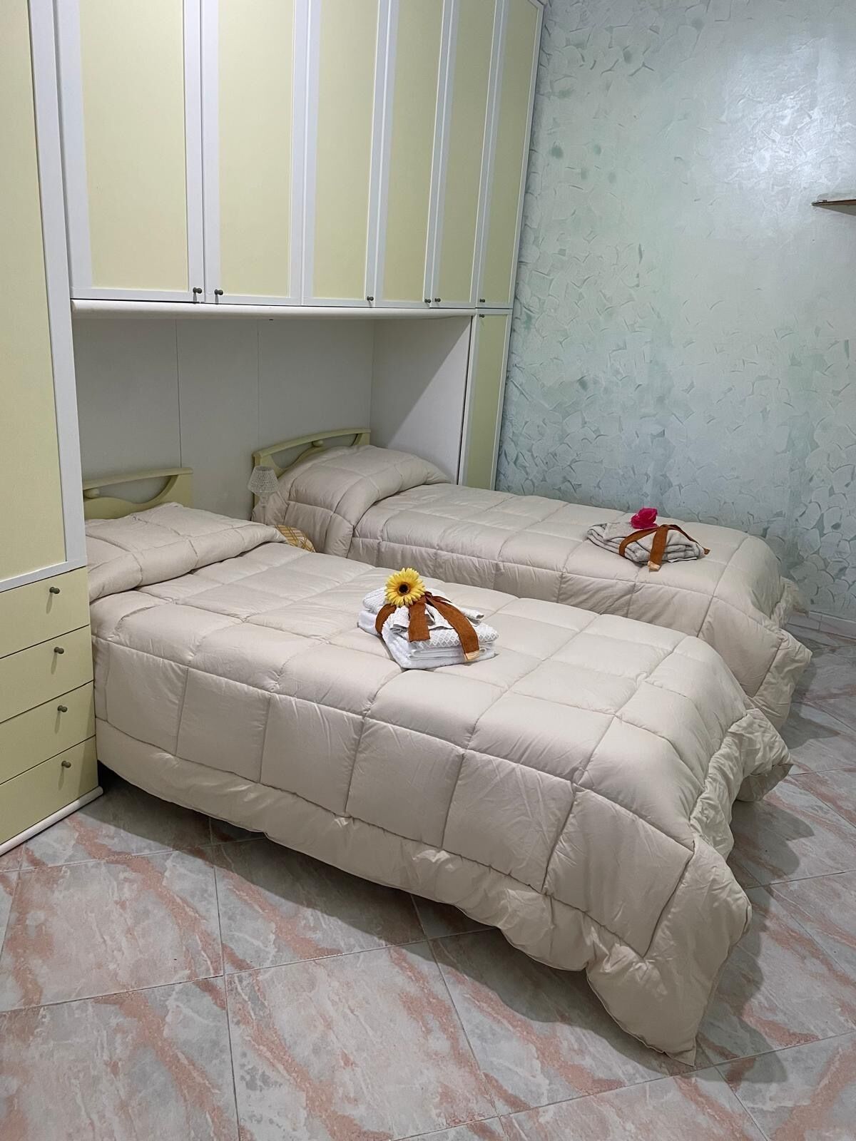 A bedroom with two beds, a wardrobe, and a marble-tiled floor.
