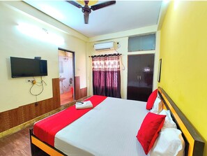 A hotel room with a bed, a television mounted on the wall, an air conditioning unit, and a wardrobe. - Hotel Varanasi Paradise  (Varanasi)