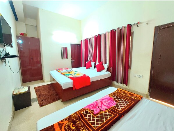 A bedroom with a bed, bedside tables, a wardrobe, a mirror, and a TV. - Hotel Varanasi Paradise  (Varanasi)