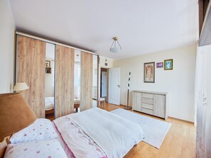 A bedroom with a bed, a wardrobe, a desk, and a chair.