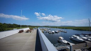 A marina with boats docked, a wooden deck with picnic tables, and a grassy landscape in the background. - Holiday Home in Swinoujscie Near Baltic Beach (Swinoujscie)