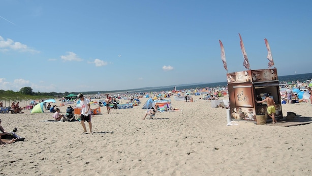 A beach with people, tents, and a cafe structure. - Holiday Home in Swinoujscie Near Baltic Beach (Swinoujscie)