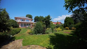 A house with a stone pathway leading to a front door, surrounded by lush greenery and a well-maintained lawn. - Holiday Home in Swinoujscie Near Baltic Beach (Swinoujscie)